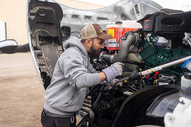 bearded car mechanic inspecting the engine compartment of a large truck